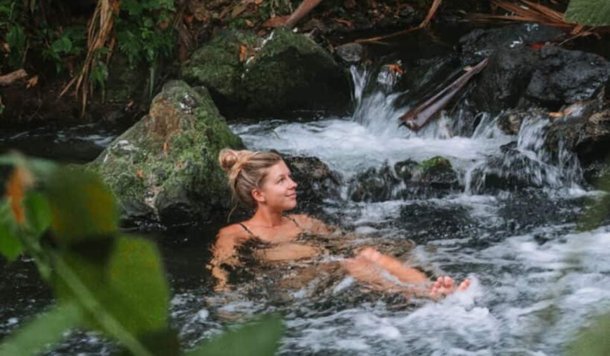 Woman relaxing in El Chollín thermal river, La Fortuna, Costa Rica