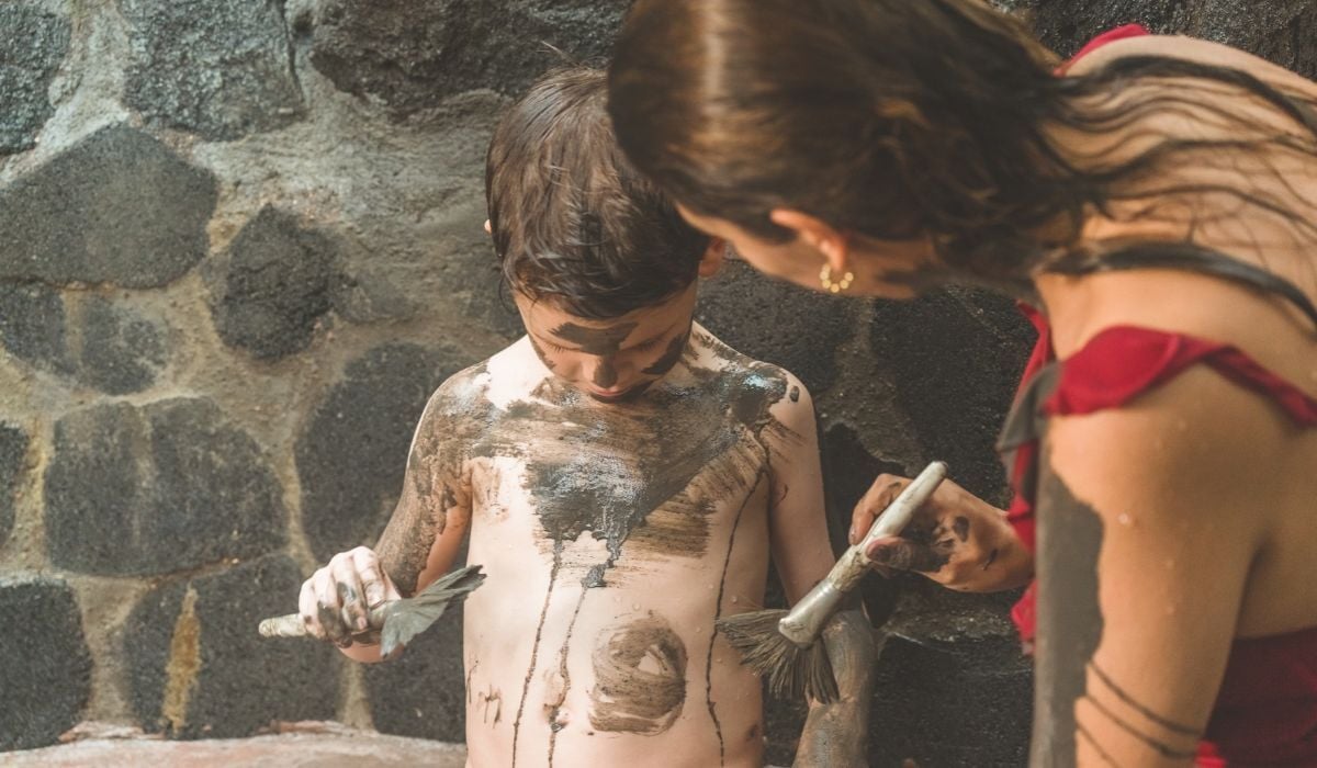 Child enjoying the volcanic mud ritual with his mother at Montaña de Fuego, La Fortuna